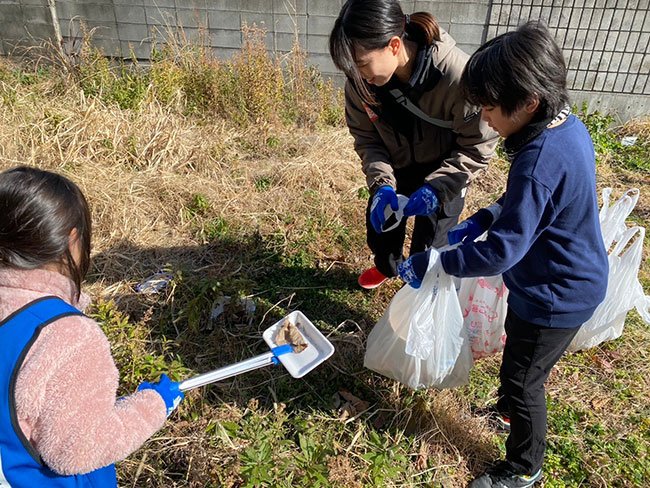 ごみを集める子ども2人とそれを手伝う成人女性