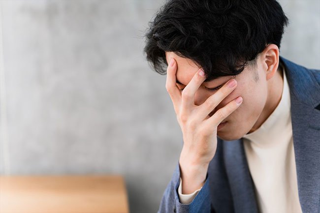 頭を押さえる男性のイメージ